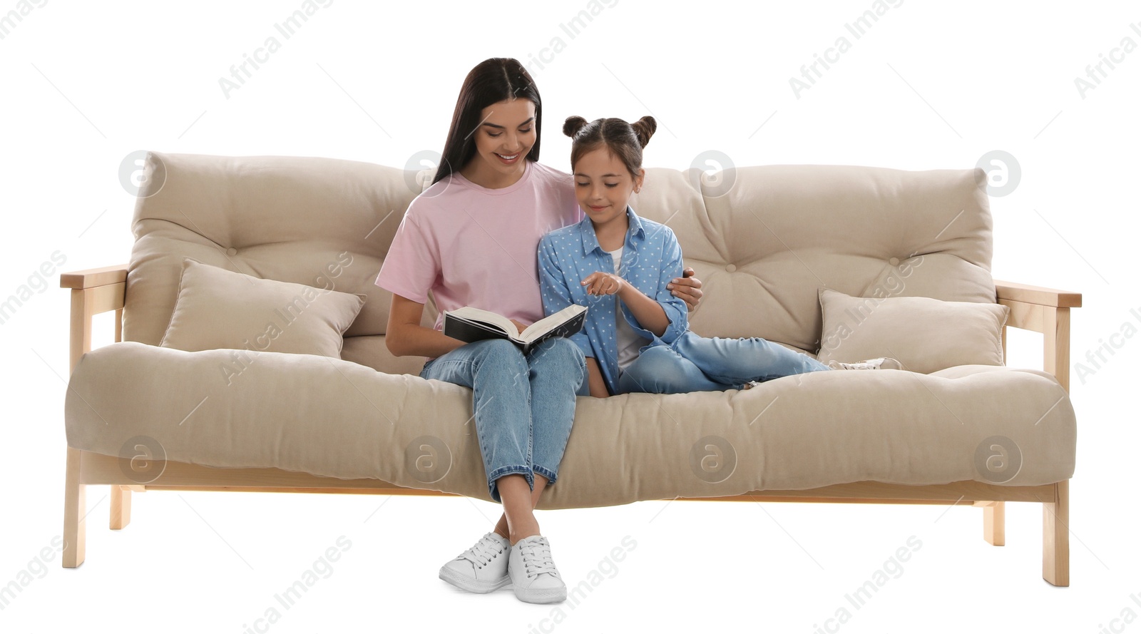 Photo of Young woman and her daughter reading book on comfortable sofa against white background