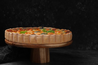 Photo of Delicious homemade quiche with salmon and broccoli on wooden stand