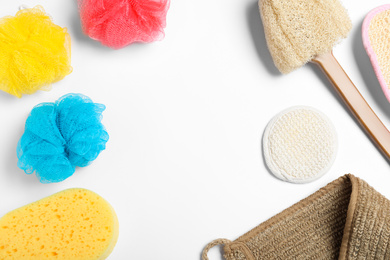 Photo of Plastic and natural shower sponges on white background, top view. Recycling concept