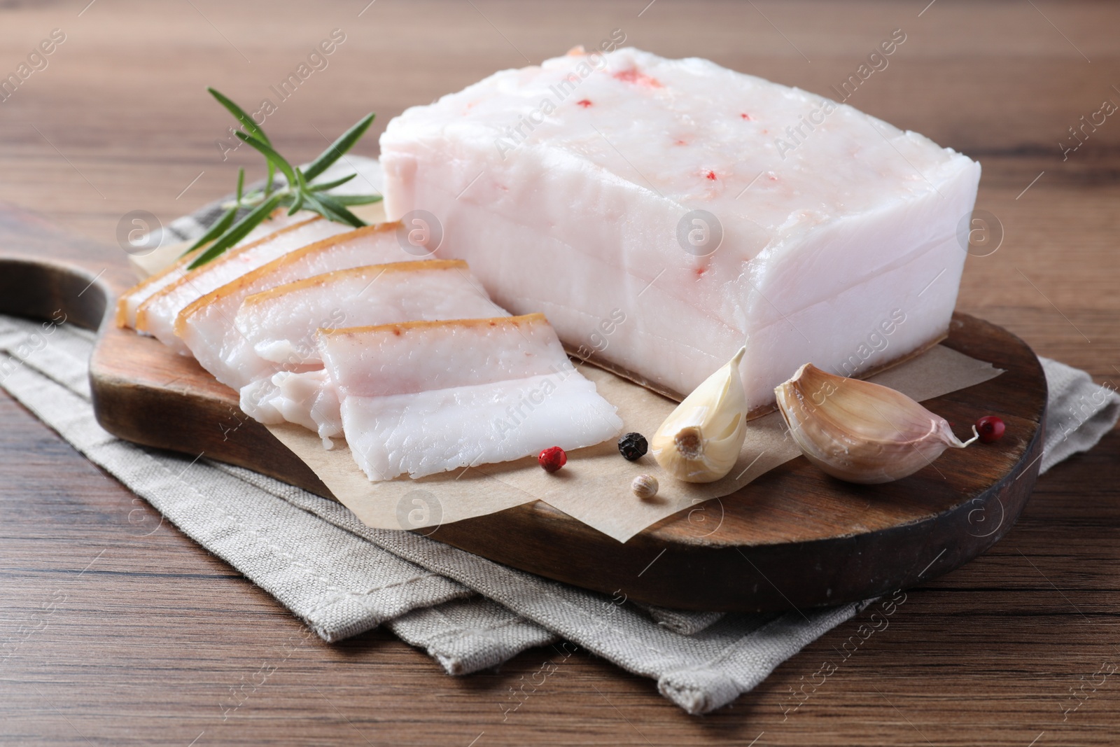 Photo of Pork fatback with rosemary, garlic and peppercorns on wooden table