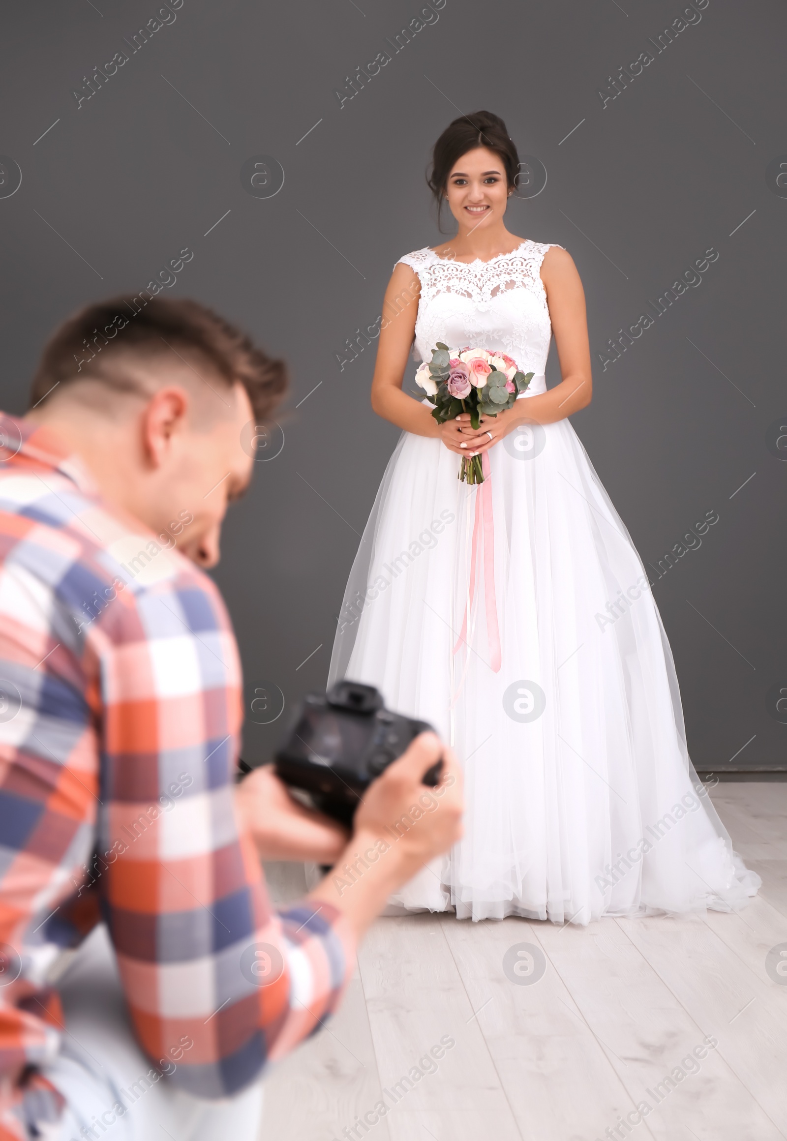 Photo of Professional photographer with camera and beautiful bride in studio
