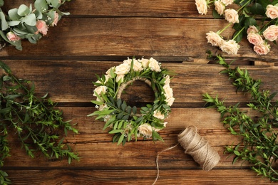 Photo of Flat lay composition with wreath made of beautiful flowers on wooden table