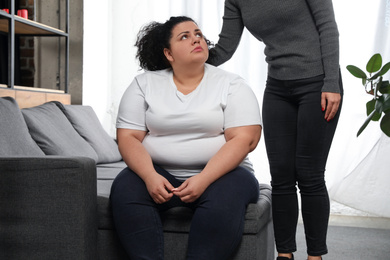 Woman comforting her depressed overweight friend at home