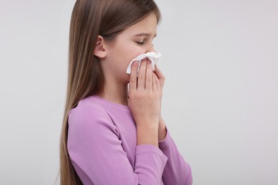 Sick girl with tissue coughing on light background, space for text