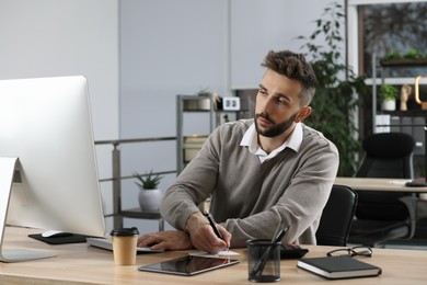 Photo of Man working on computer at table in office