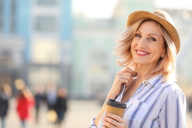 Photo of Beautiful mature woman with cup of coffee outdoors