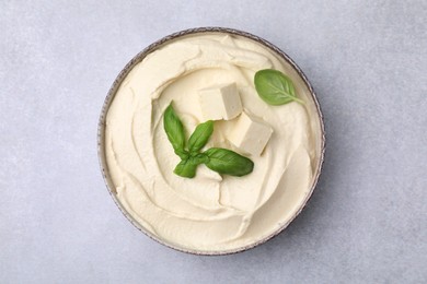 Photo of Delicious tofu sauce and basil leaves on light grey table, top view