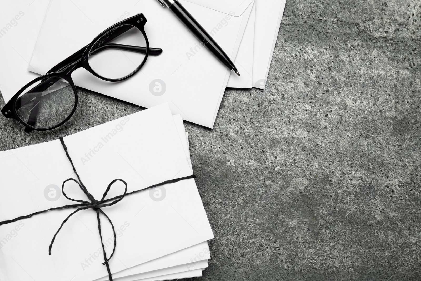 Photo of Letters, pen and glasses on grey table, flat lay. Space for text