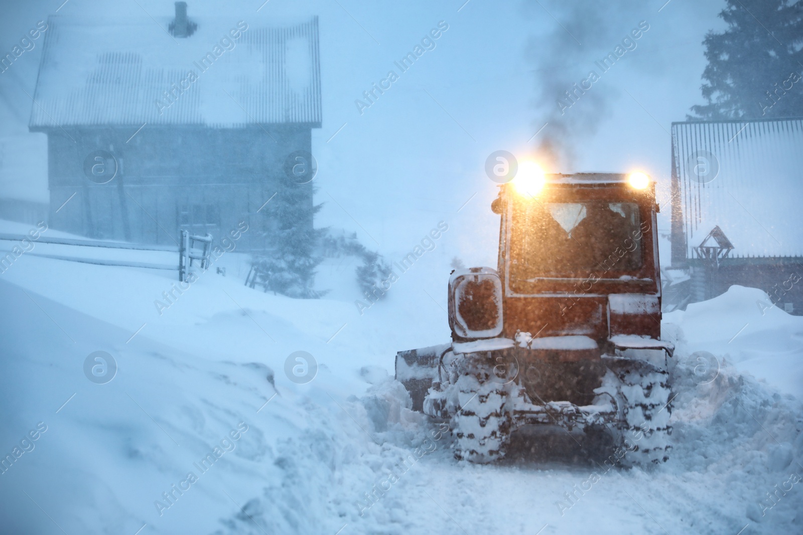 Photo of Tractor cleaning road in snowstorm. Winter season