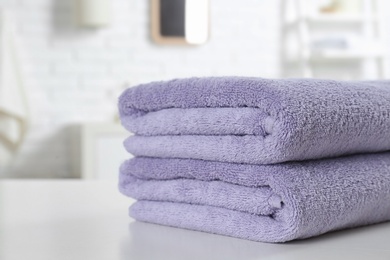 Stack of fresh towels on table in bathroom, closeup. Space for text