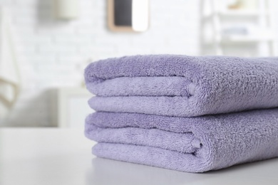 Photo of Stack of fresh towels on table in bathroom, closeup. Space for text