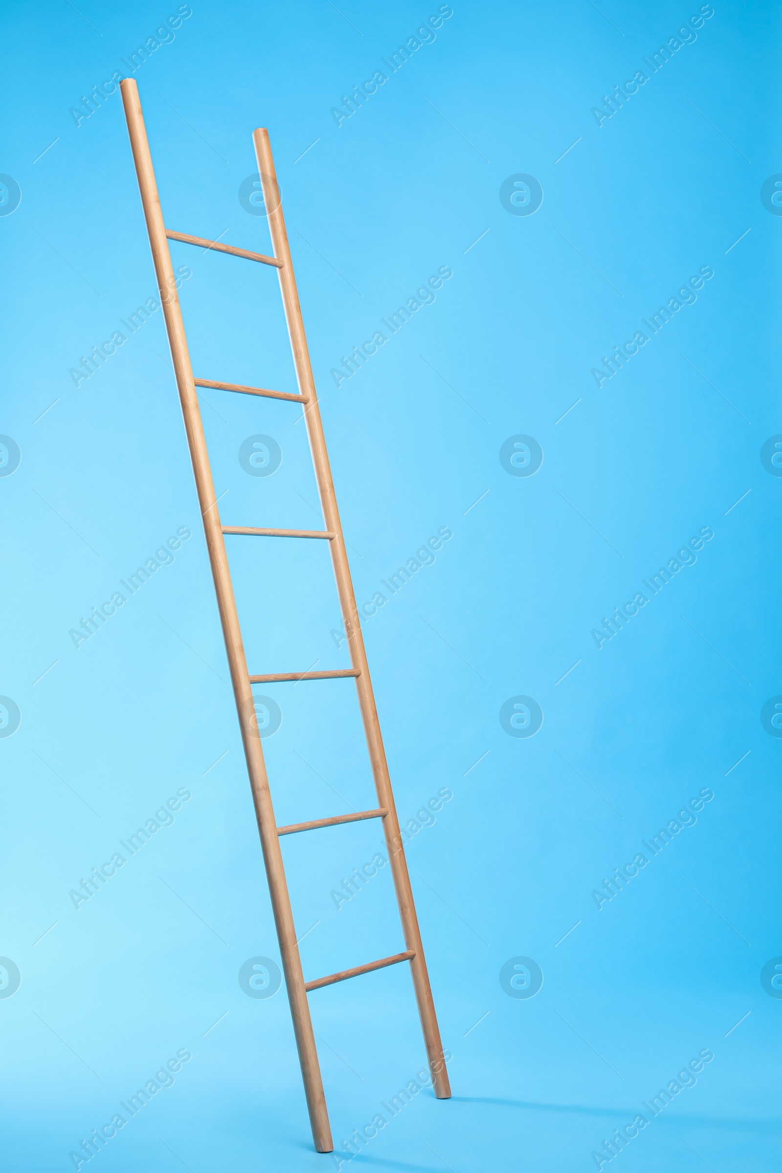 Photo of Modern wooden ladder on light blue background