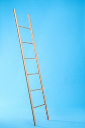 Photo of Modern wooden ladder on light blue background