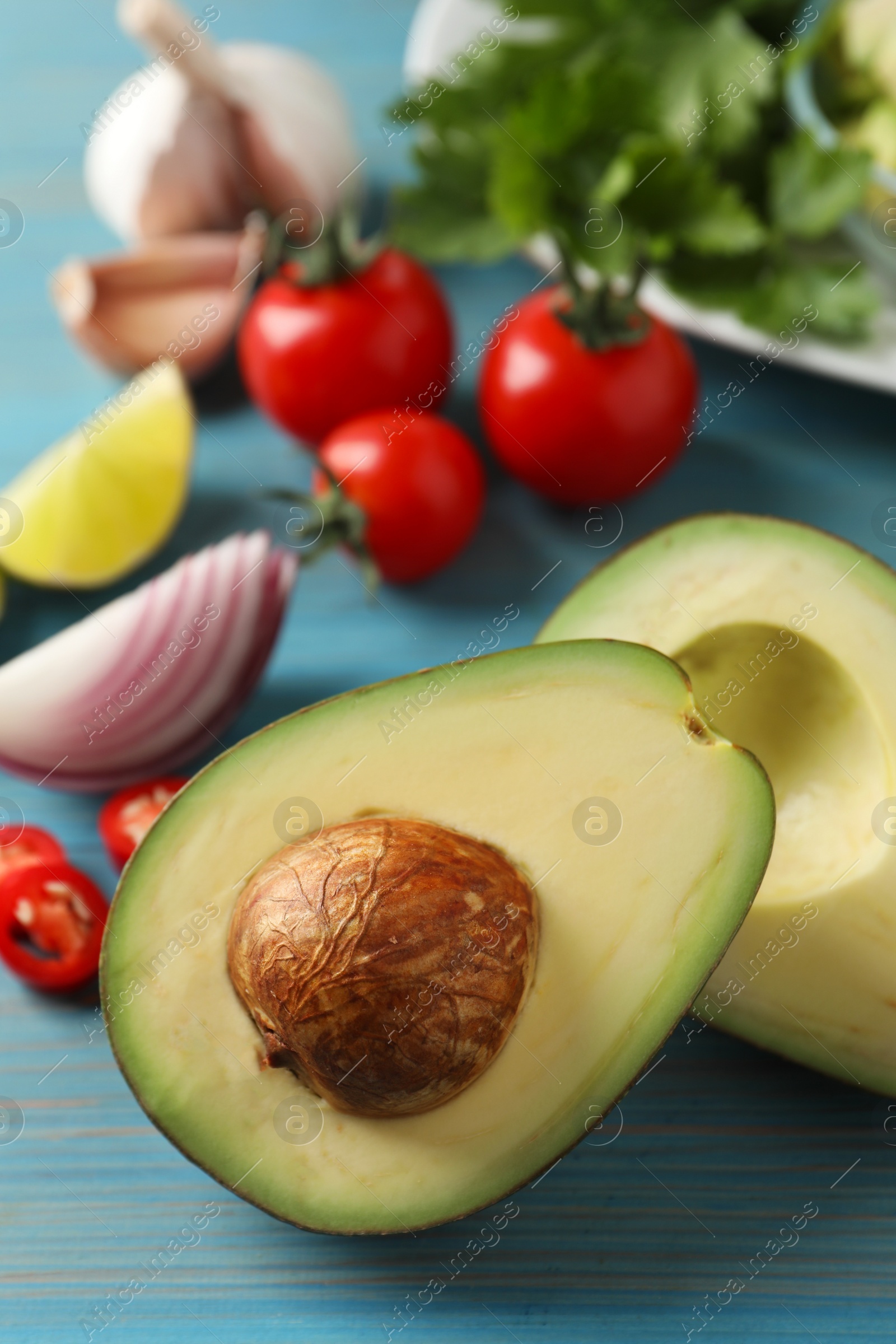 Photo of Fresh ingredients for guacamole on light blue wooden table, closeup