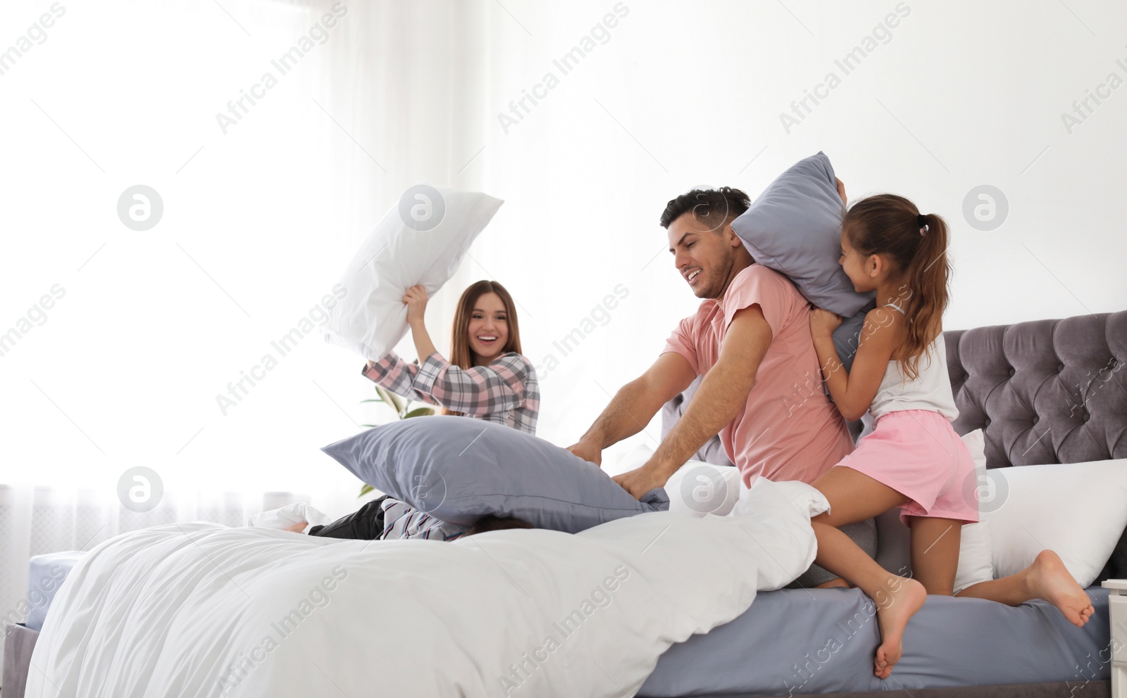 Photo of Happy family having pillow fight in bedroom