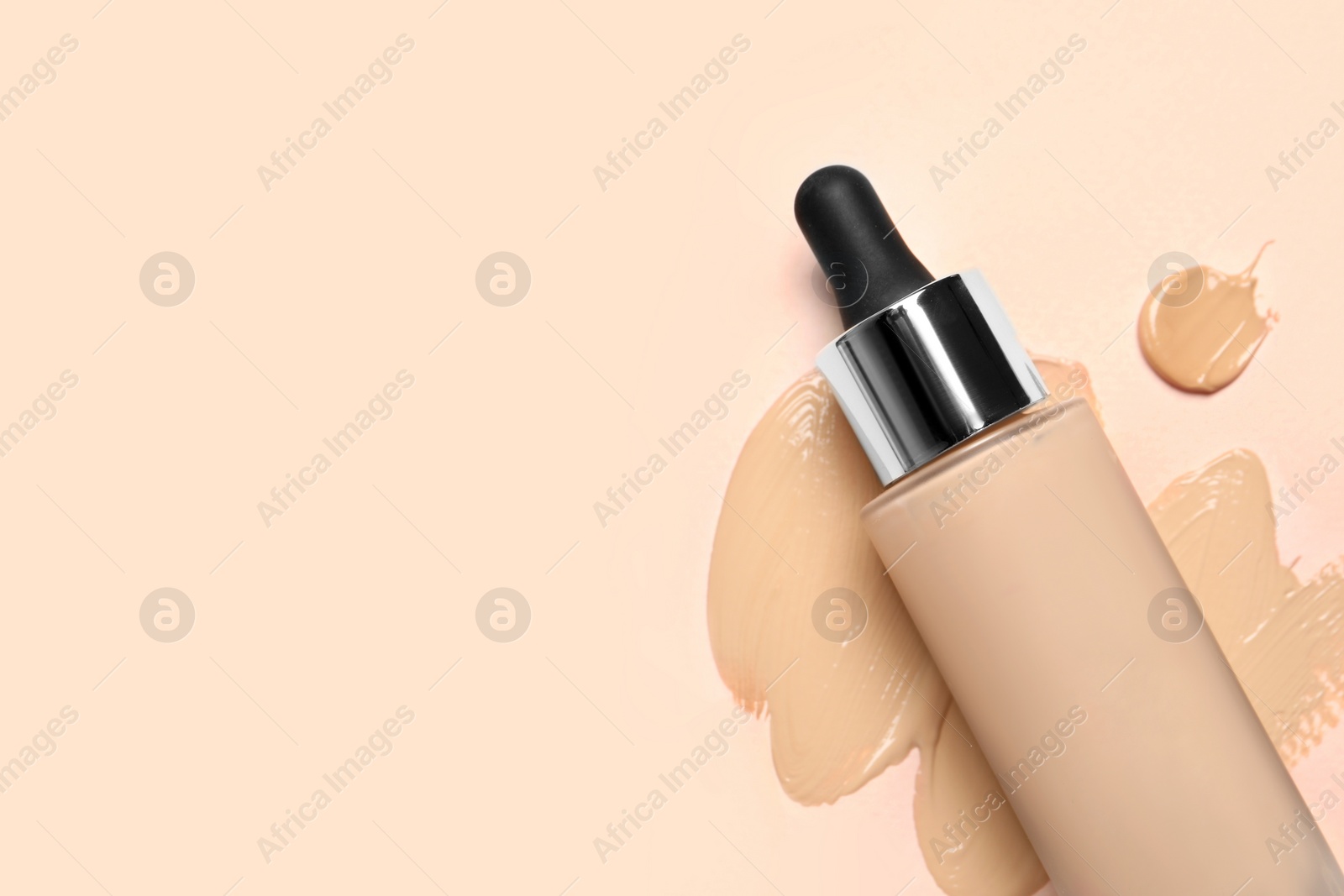 Photo of Liquid foundation and swatches on beige background, top view. Space for text