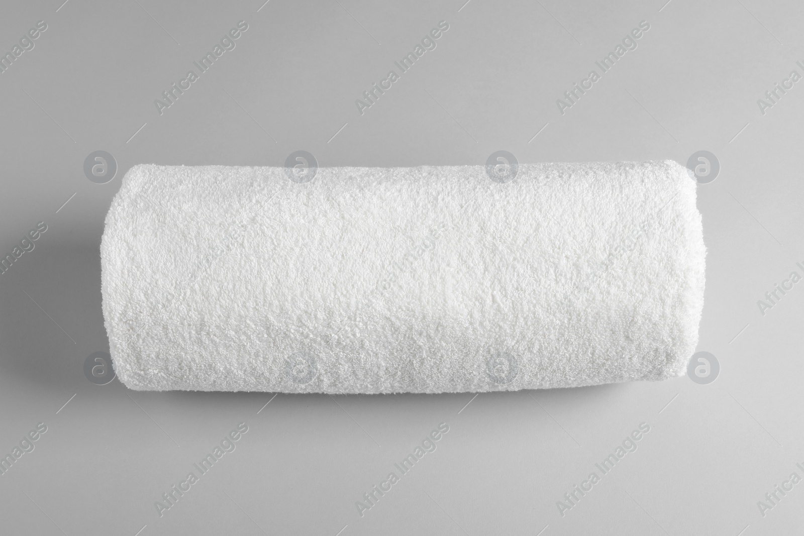 Photo of Fresh soft rolled towel on light background, top view