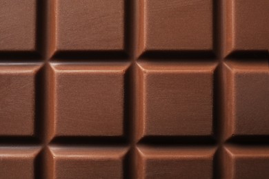 Photo of Delicious milk chocolate bar as background, top view