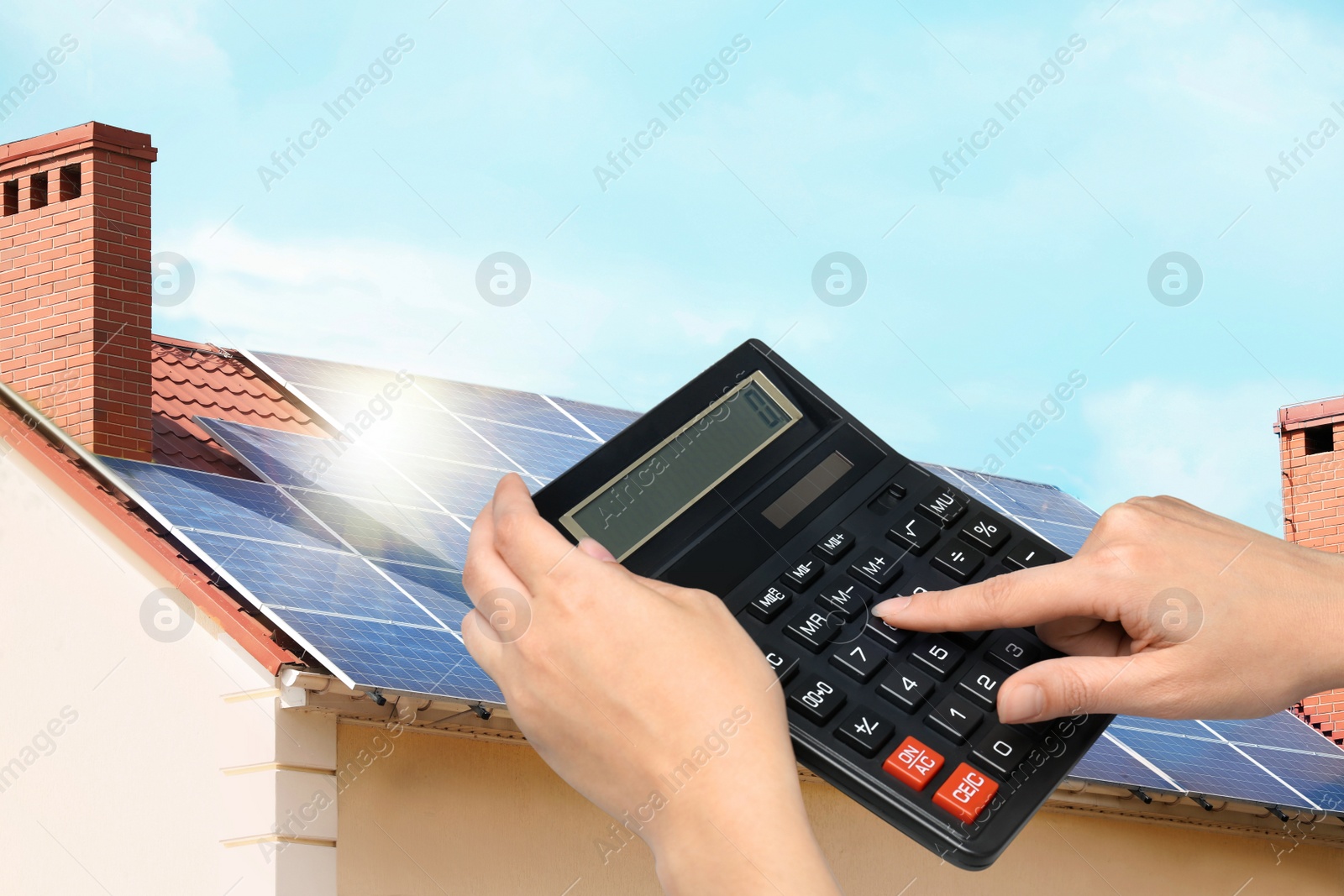 Image of Woman using calculator against house with installed solar panels. Renewable energy and money saving