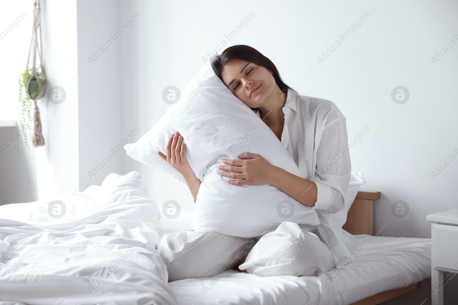 Photo of Beautiful young woman hugging pillow on bed at home