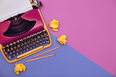 Copywriter. Vintage typewriter, crumpled paper balls and pencils on color background, top view. Space for text
