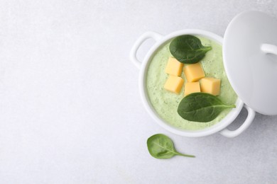 Photo of Delicious spinach cream soup with cheese in bowl on light grey table, top view. Space for text