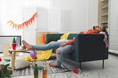 Young man sleeping on sofa in messy room after party