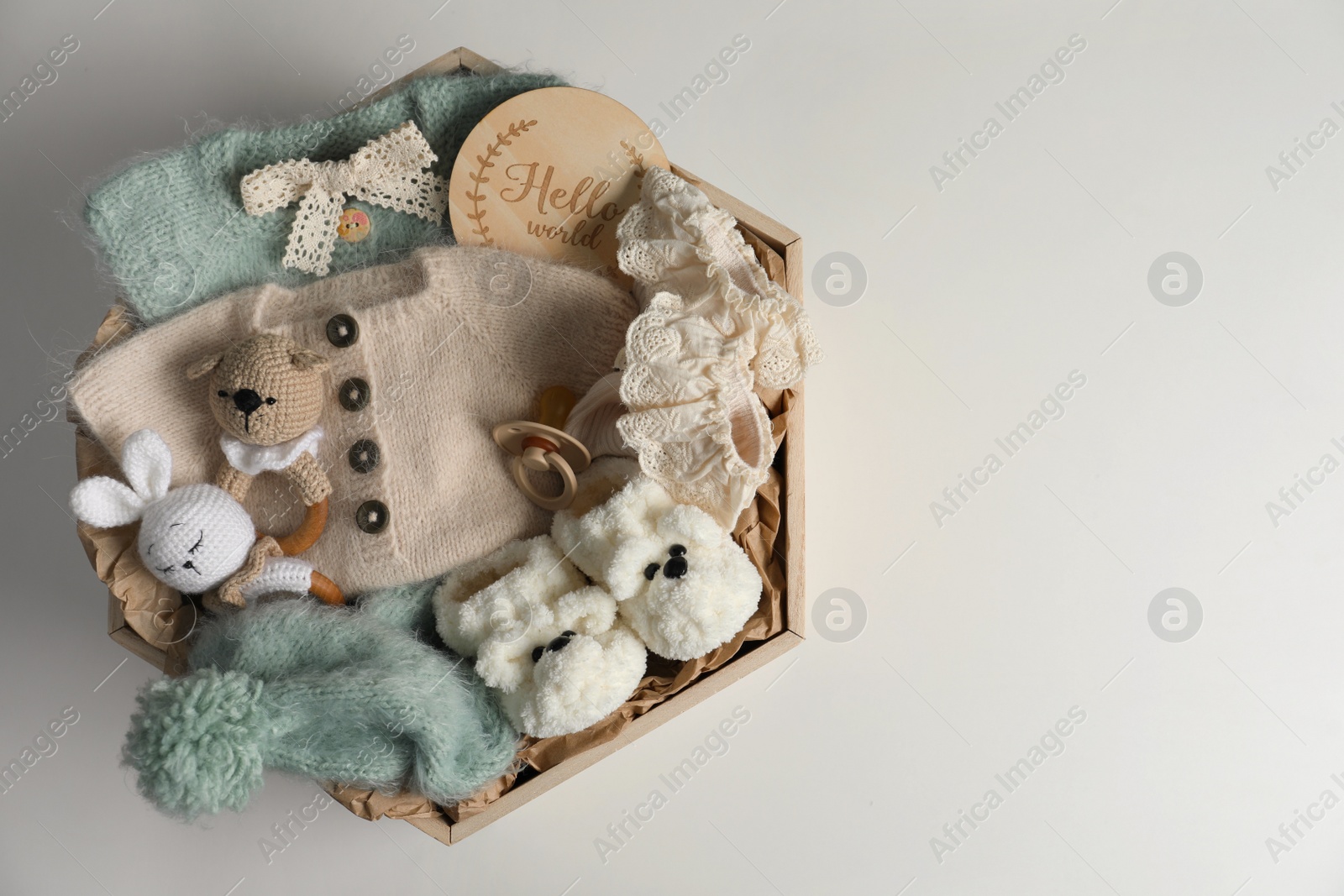 Photo of Box with baby clothes, shoes and accessories on light background, top view. Space for text