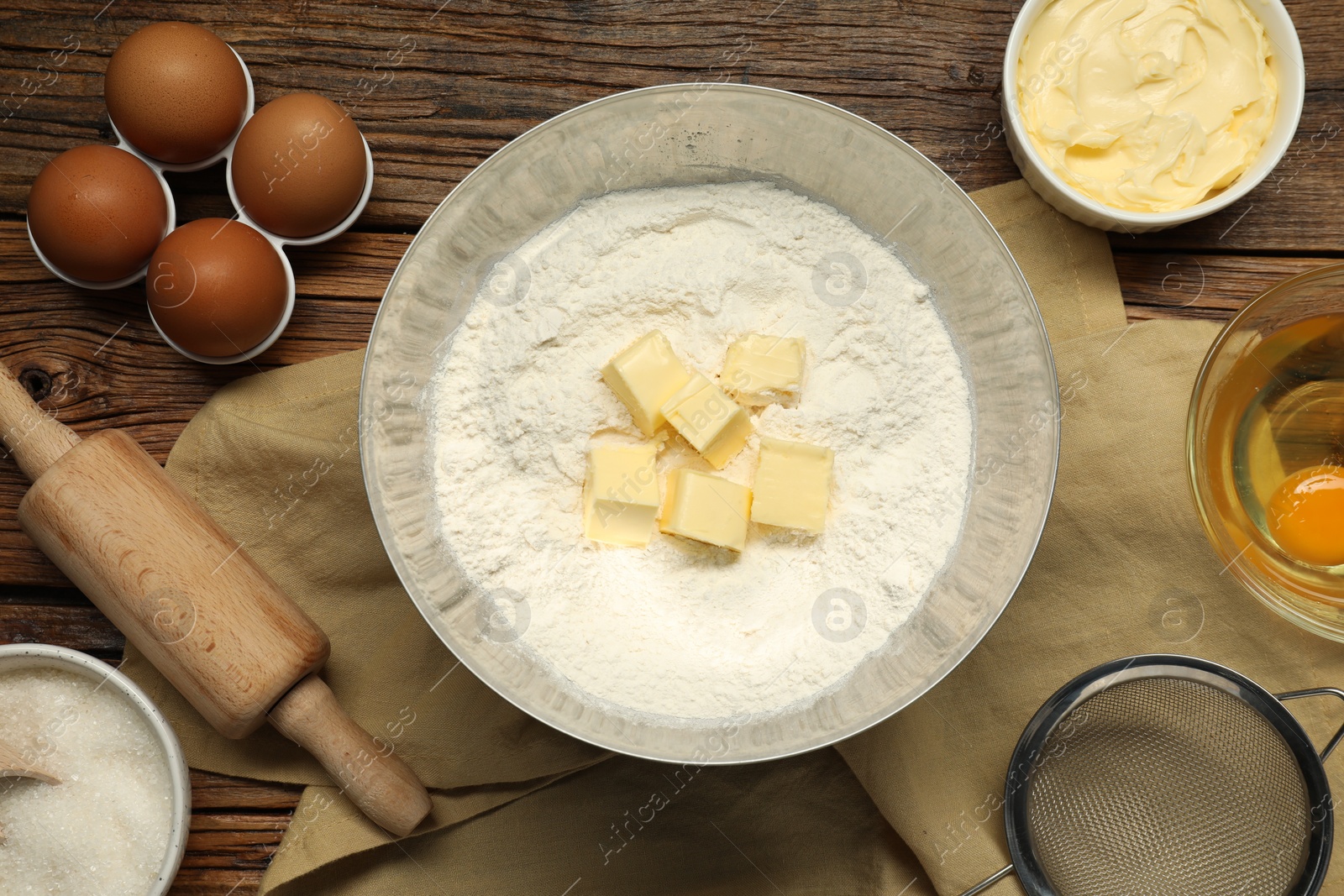 Photo of Flat lay composition with fresh butter and flour in bowl among other products on wooden table