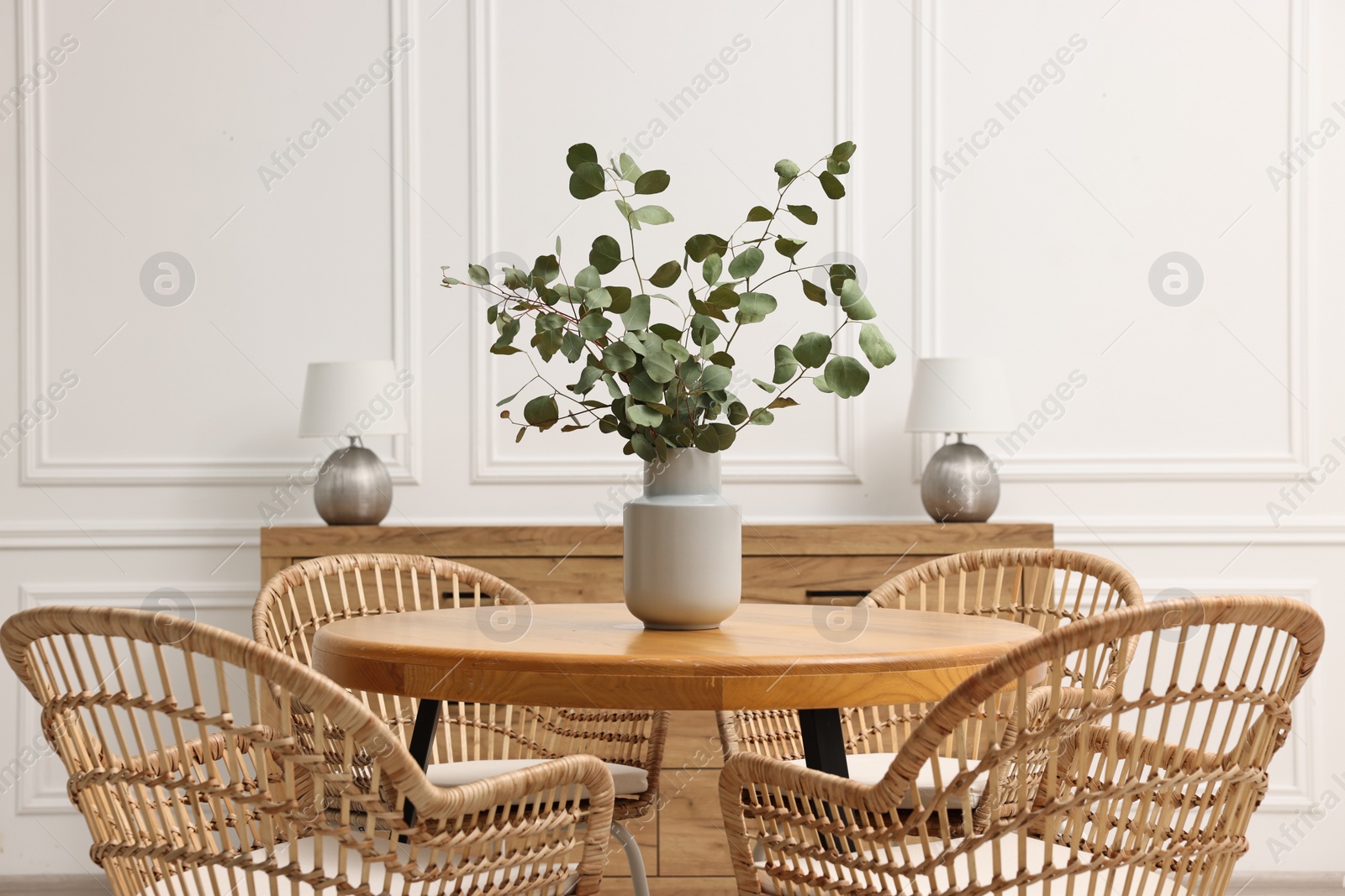 Photo of Dining room interior with comfortable furniture and eucalyptus branches