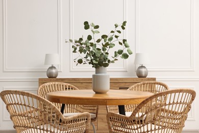 Photo of Dining room interior with comfortable furniture and eucalyptus branches