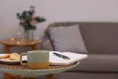 Photo of Cup of drink, cookies and notebook on coffee table indoors. Space for text