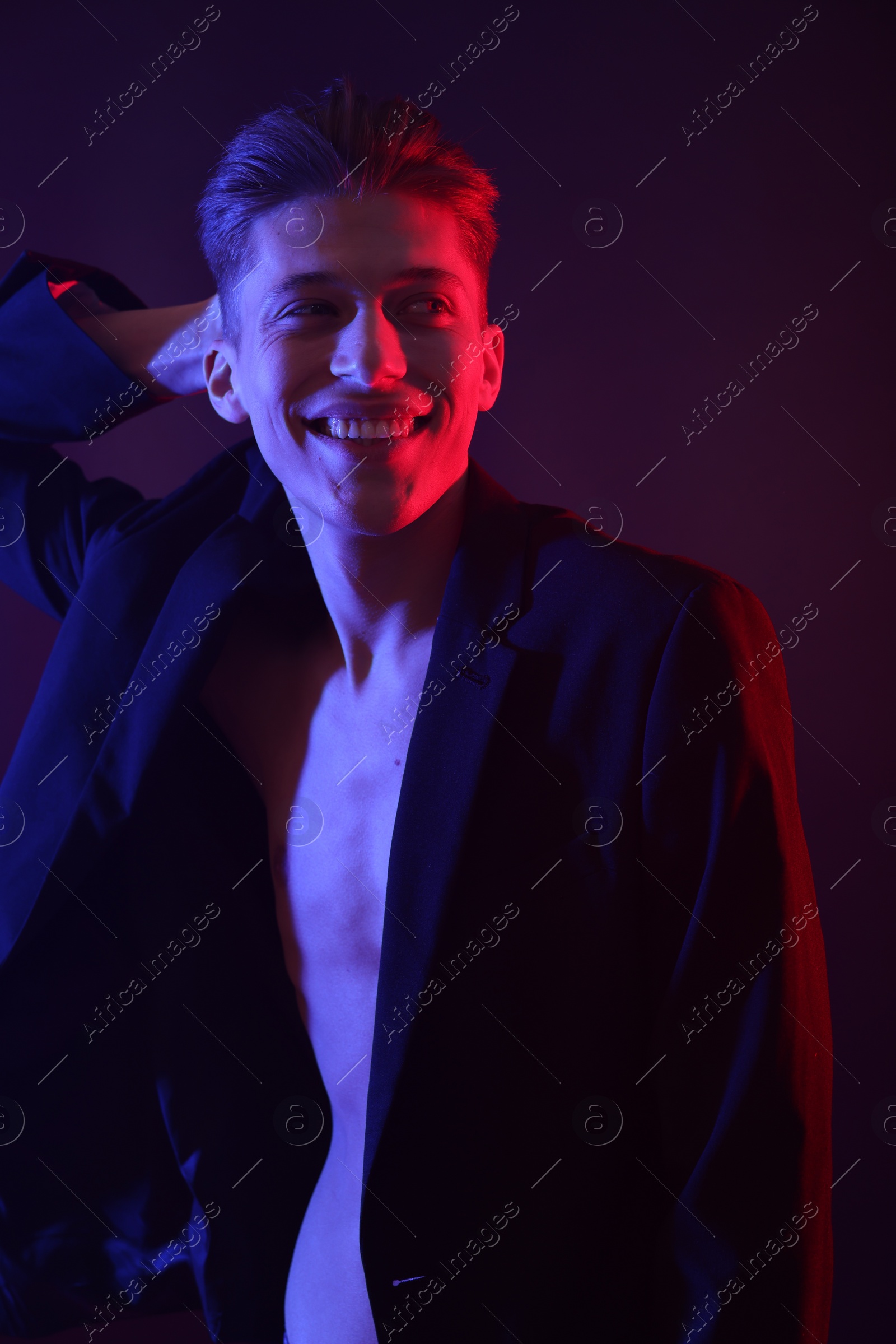 Photo of Sexy young man on dark background in neon lights