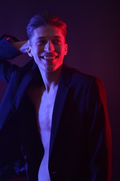 Photo of Sexy young man on dark background in neon lights