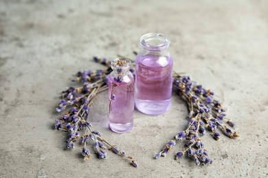 Natural herbal oil in glass bottles and lavender flowers on color background