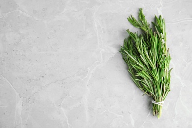 Bunch of fresh rosemary on grey marble table, top view with space for text