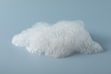 Photo of Fluffy bath foam on light blue background