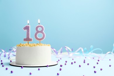 Photo of Coming of age party - 18th birthday. Delicious cake with number shaped candles on light blue background, space for text