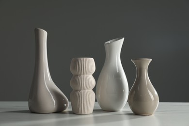 Photo of Different stylish vases on white marble table