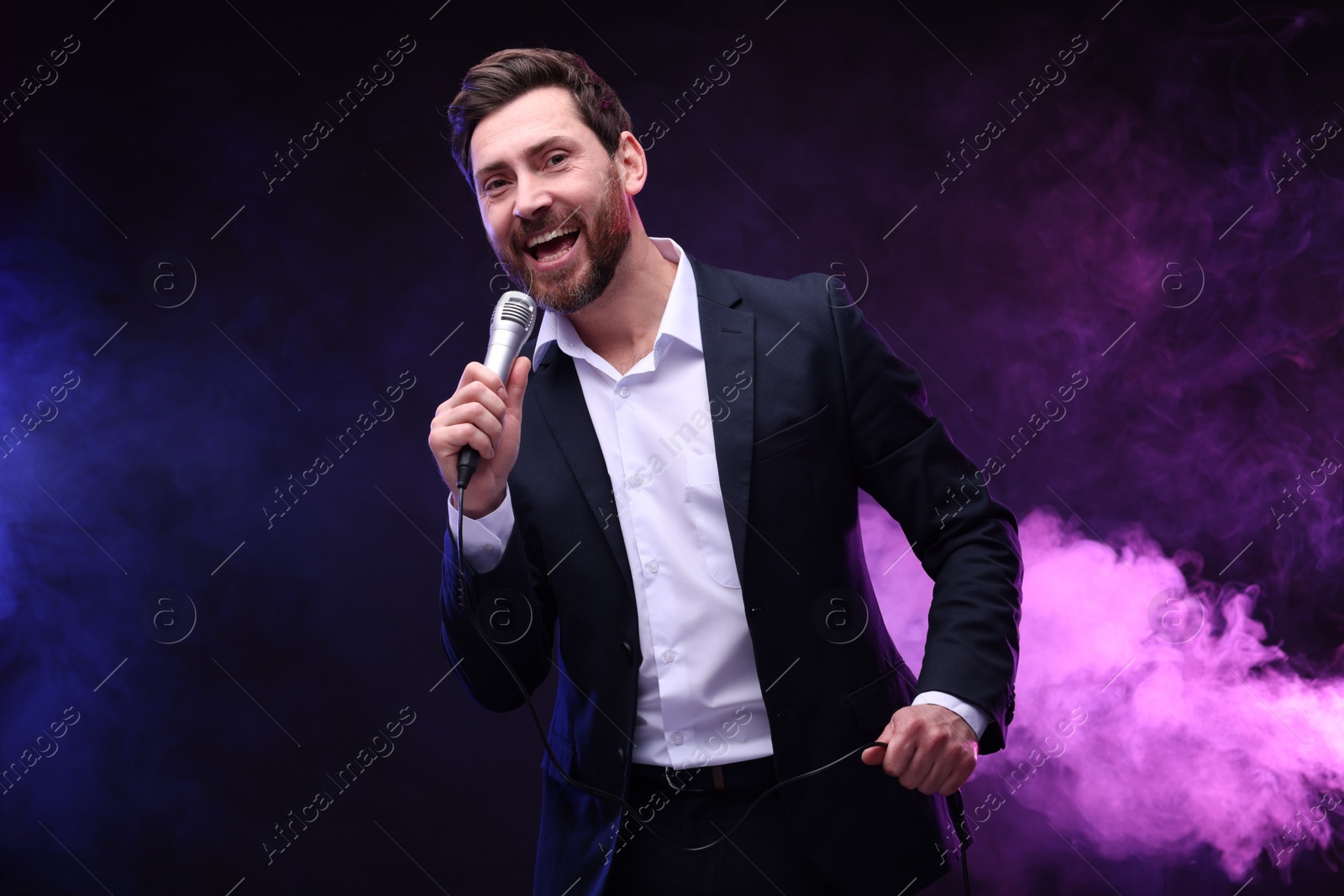 Photo of Emotional man with microphone singing in neon lights