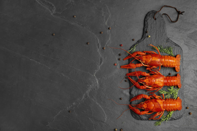 Photo of Delicious boiled crayfishes with dill and pepper on black table, flat lay. Space for text