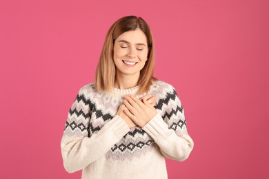 Portrait of woman holding hands near heart on color background