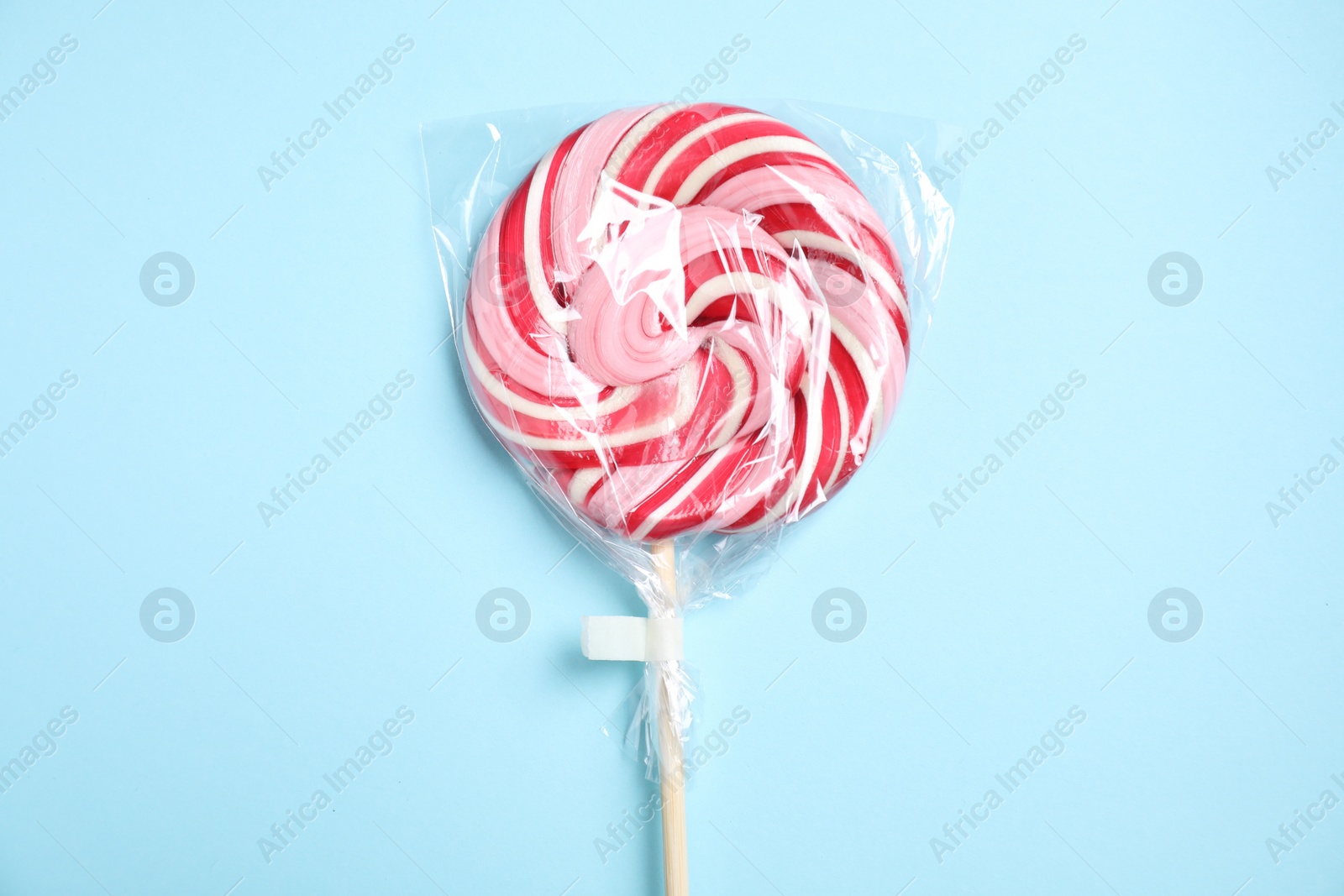 Photo of Packed bright lollipop on light blue background, top view