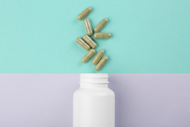 Photo of Bottle and vitamin capsules on color background, top view