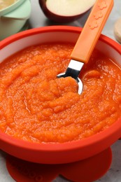 Healthy baby food. Bowl with delicious carrot puree on light grey table, closeup