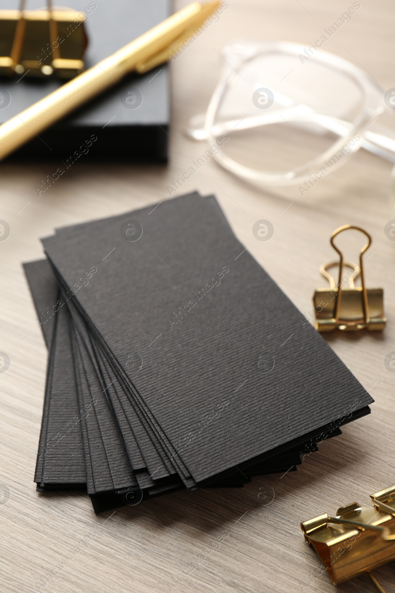 Photo of Blank black business cards and other stationery on wooden table, closeup. Mockup for design