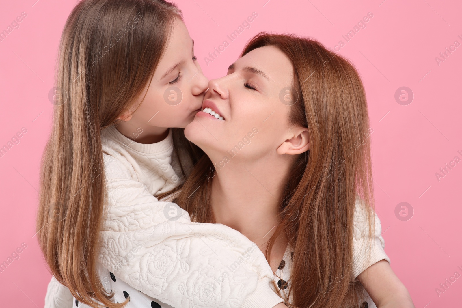 Photo of Portrait of happy mother and her cute daughter on pink background, closeup