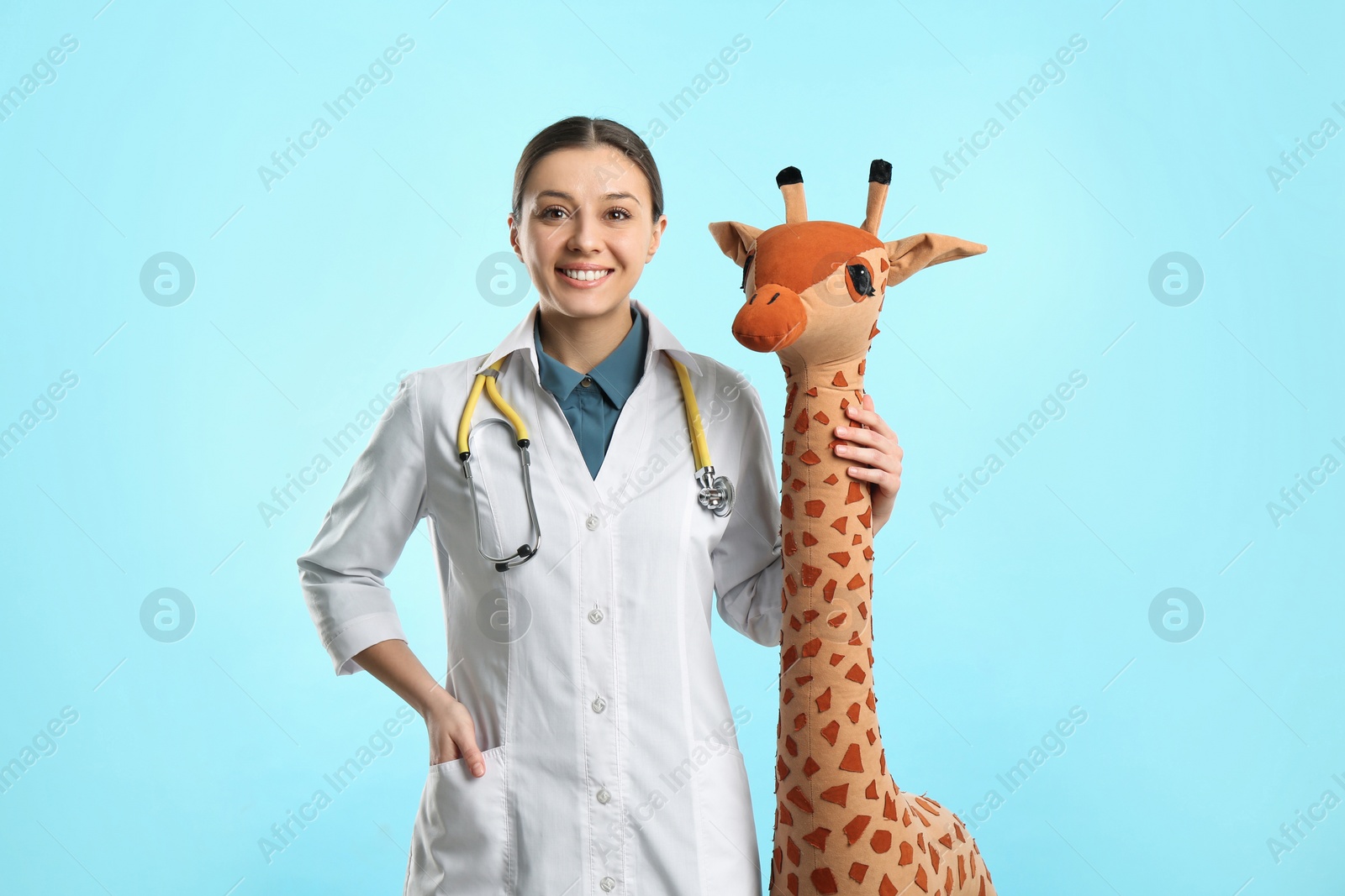 Photo of Pediatrician with toy giraffe and stethoscope on turquoise background