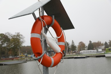 Photo of Orange lifebuoy near river outdoors, space for text