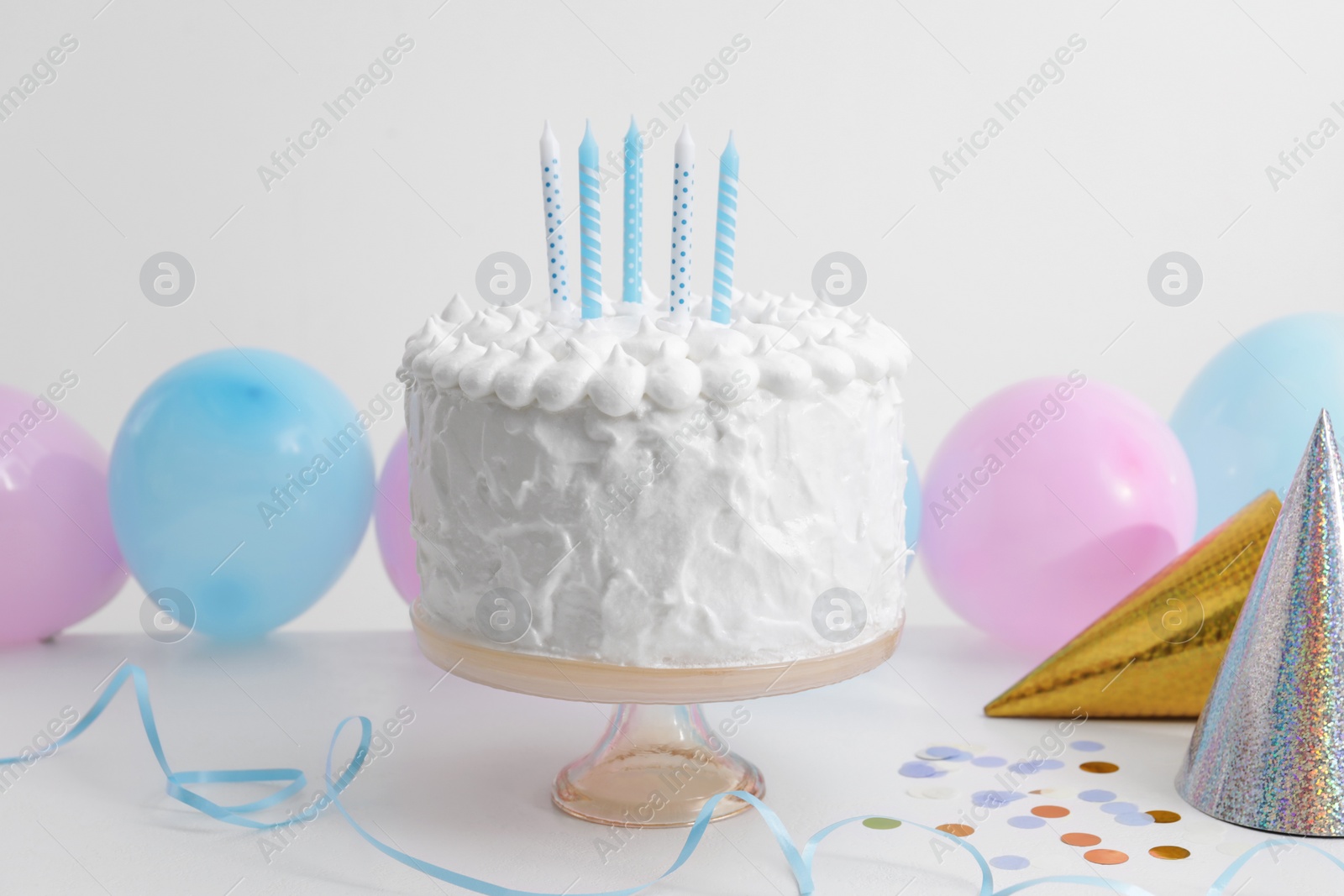 Photo of Delicious cake with candles and decorations on white table
